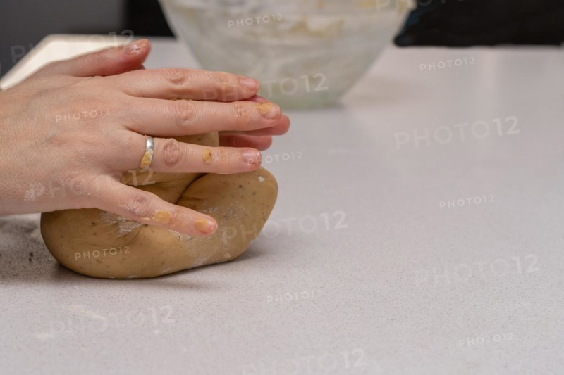 Close-up of womans hands kneading fresh dough for making cookies in her kitchen