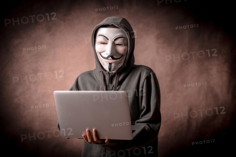 Man with anonymous mask with sweatshirt and with a laptop