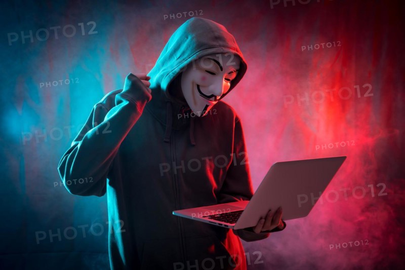 Hacker with an anonymous mask with a computer and making a fight symbol
