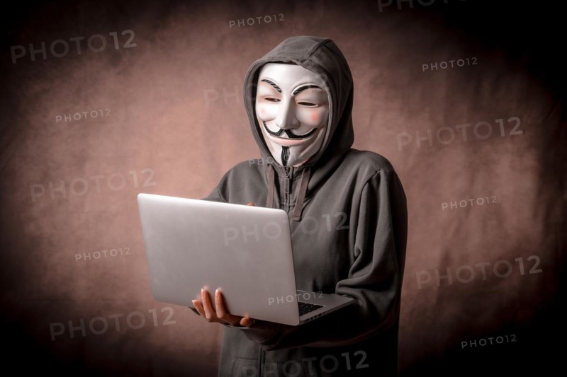 Man with anonymous mask with sweatshirt and with a laptop