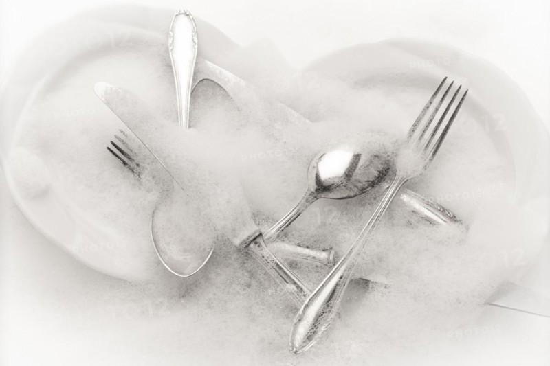 Freshly washed crockery and cutlery in soapy water