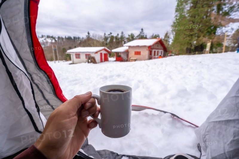 Having a coffee in a cup inside a tent on a winter morning