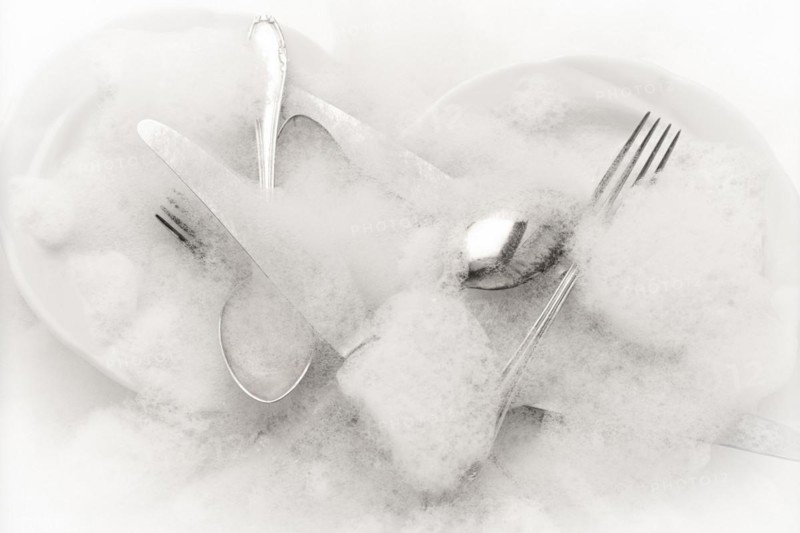 Freshly washed crockery and cutlery in soapy water