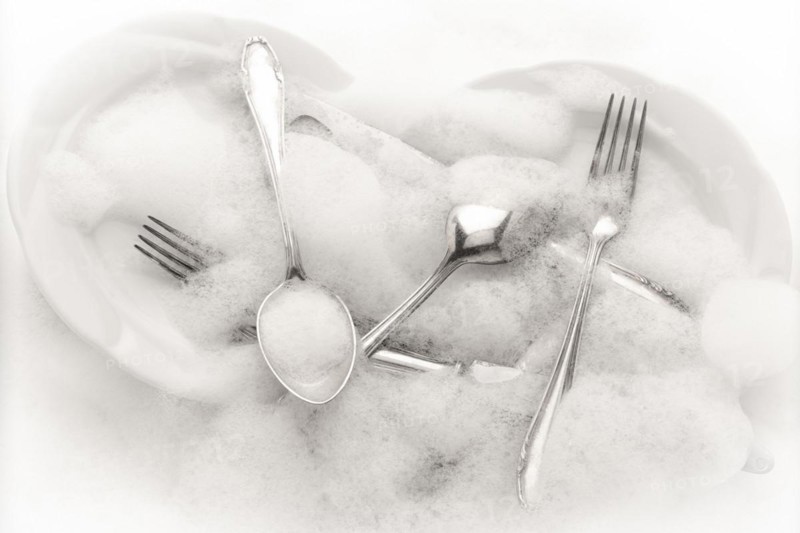 Freshly washed crockery and cutlery in soapy water