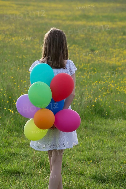 Gilr from behind with colorful balloons in her hands