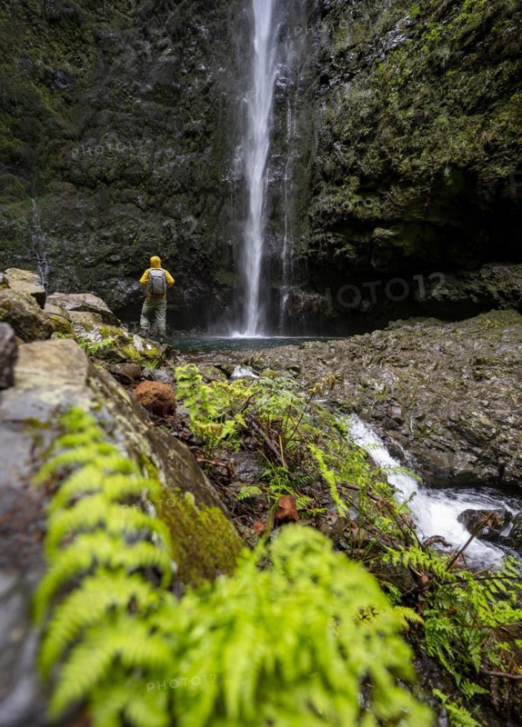 Hikers in front of a waterfall on a steep rock face