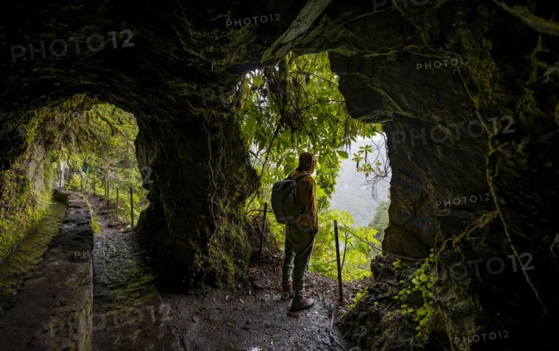 Hikers on a trail along a levada through a tunnel