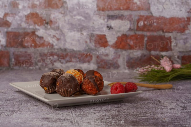 Sweet truffles of different flavors on a white ceramic plate