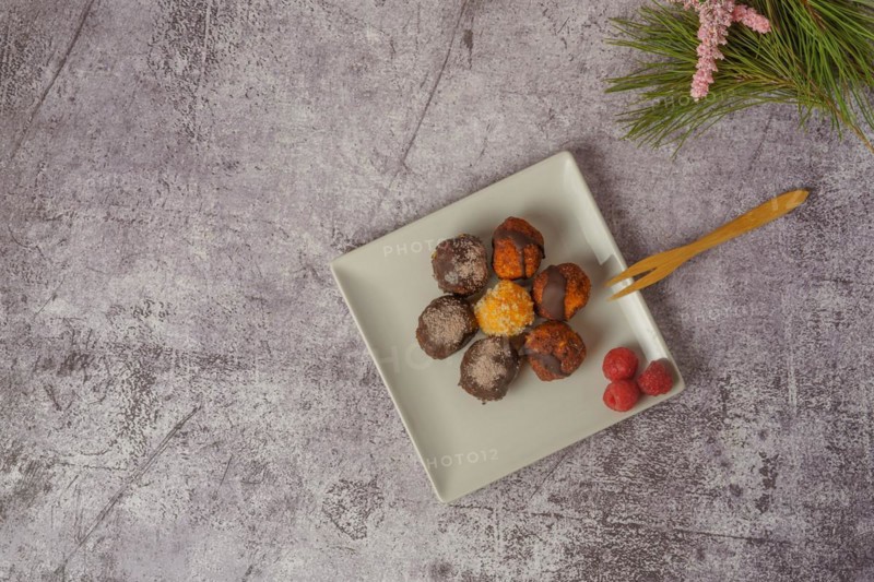 Sweet truffles of different flavors on a white ceramic plate