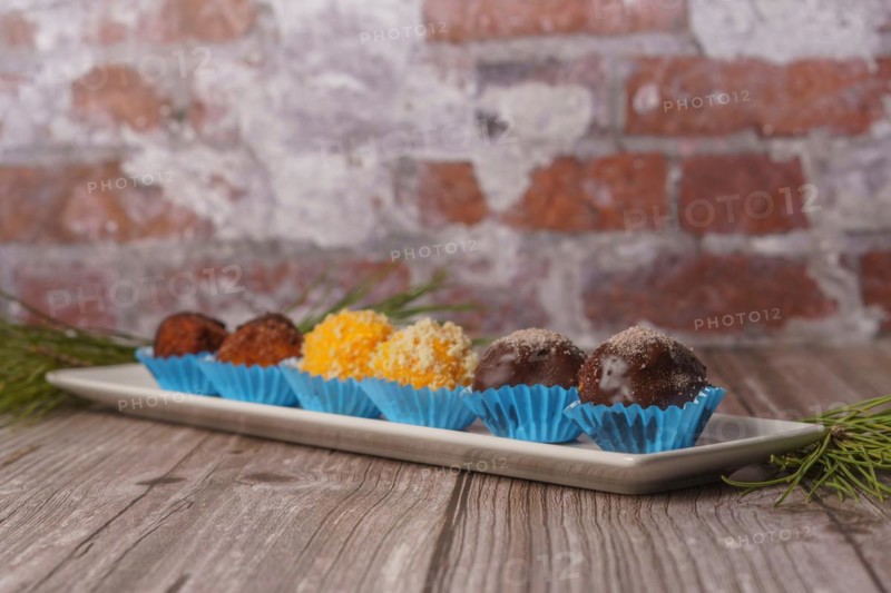 Sweet truffles in different flavors on a white ceramic tray on a wooden table