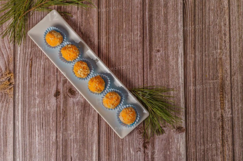 Sweet truffles in different flavors on a white ceramic tray on a wooden table