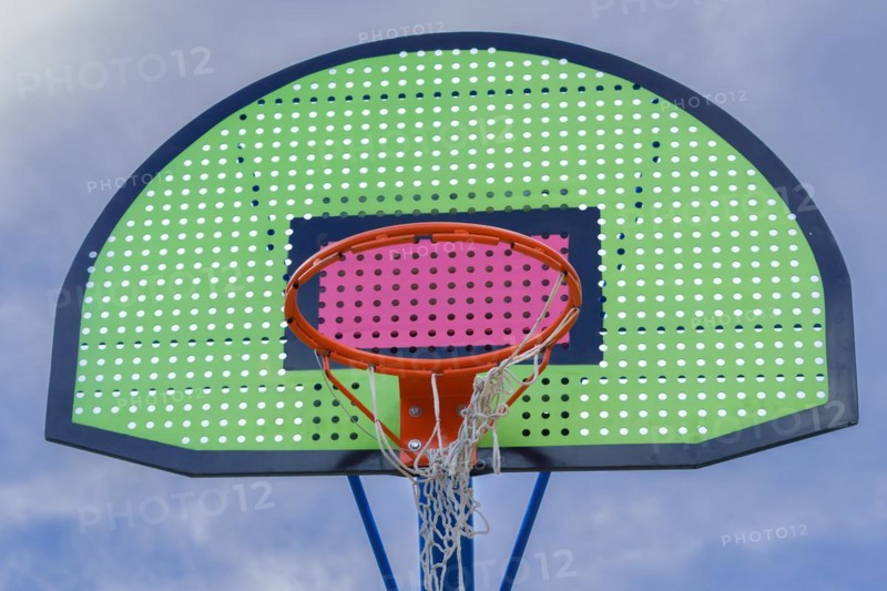 Colorful basketball basket with broken net and blue sky background with clouds