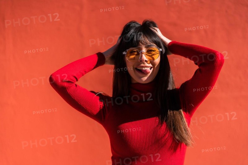 Posing brunette girl smiling in a dress and orange sunglasses in spring