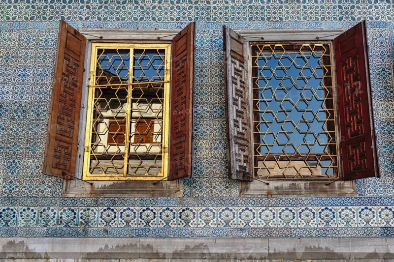 Two barred windows with shutters in mosaic wall