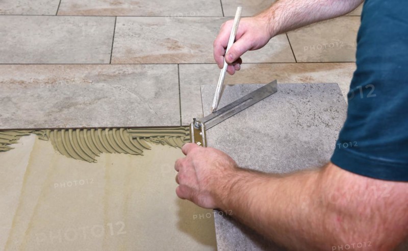 Tiler has applied tile adhesive and is sticking on new tiles