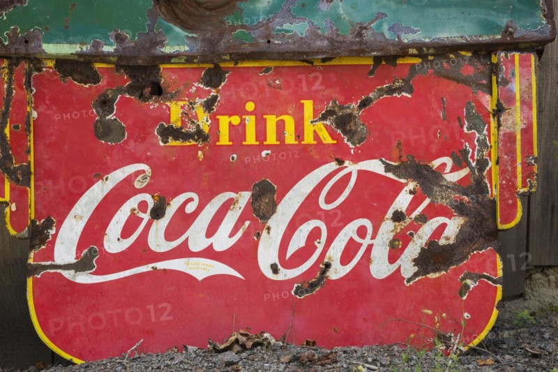 Vintage Drink Coca Cola advertising sign in front of wood plank storage shed