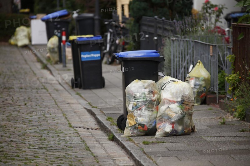 Blue bins for waste paper and yellow bags for plastic waste standing on the street