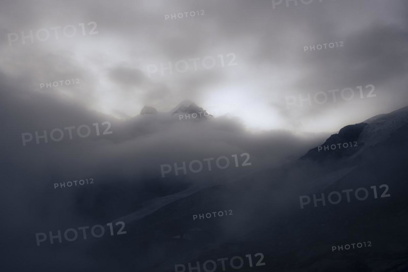 Summit of Piz Rosegg with Rosegg glacier and dramatic clouds at blue hour