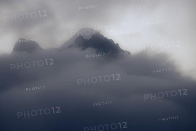 Peak of Piz Rosegg in dramatic clouds at blue hour