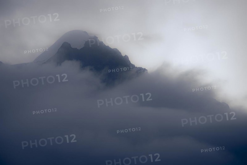 Peak of Piz Rosegg in dramatic clouds at blue hour