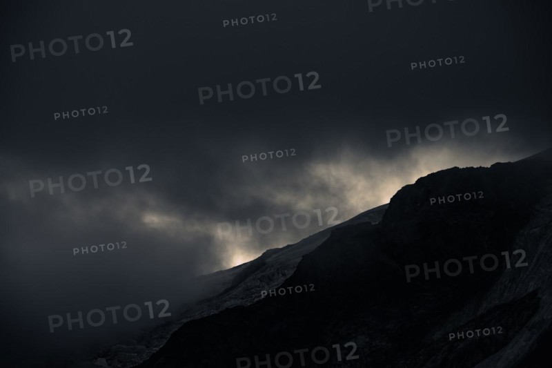 Peak of Piz Rosegg in dramatic clouds at blue hour