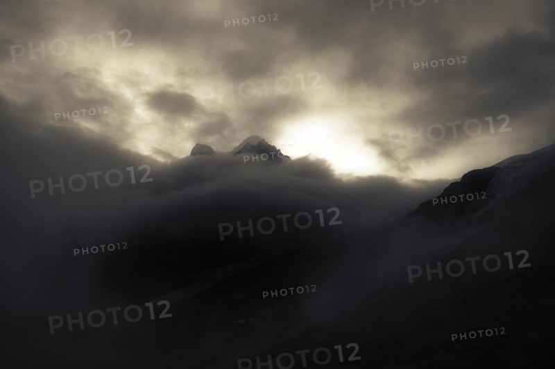 Peak of Piz Rosegg in dramatic clouds at blue hour