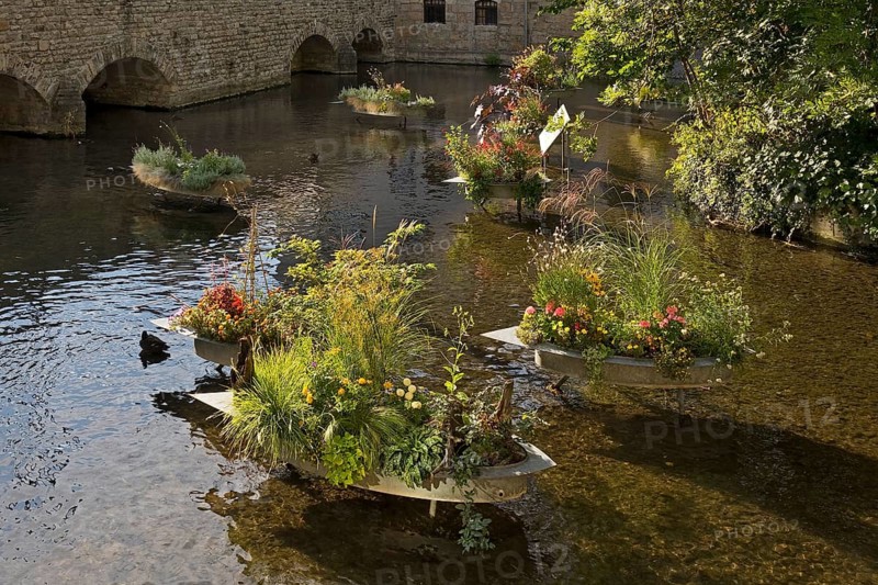 Zinc tubs in the shape of boats with flowering plants on the river Gera