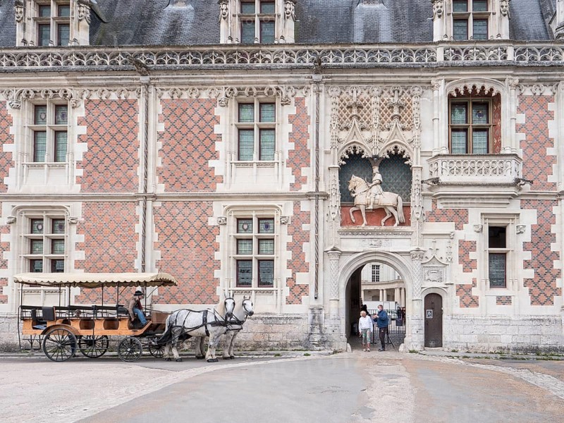 Equestrian statue of Louis XII above the entrance to the Chateau Royal de Blois and a carriage with two white horses