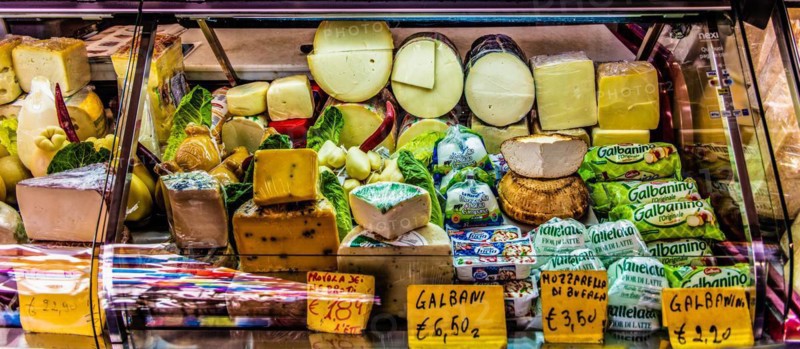 Ham and cheese stall at the historic fish market La pescheria with an abundance of colourful seafood