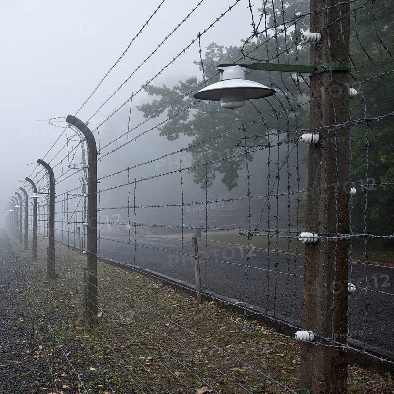 Reconstructed camp fence with crematorium in the fog at beech forest concentration camp