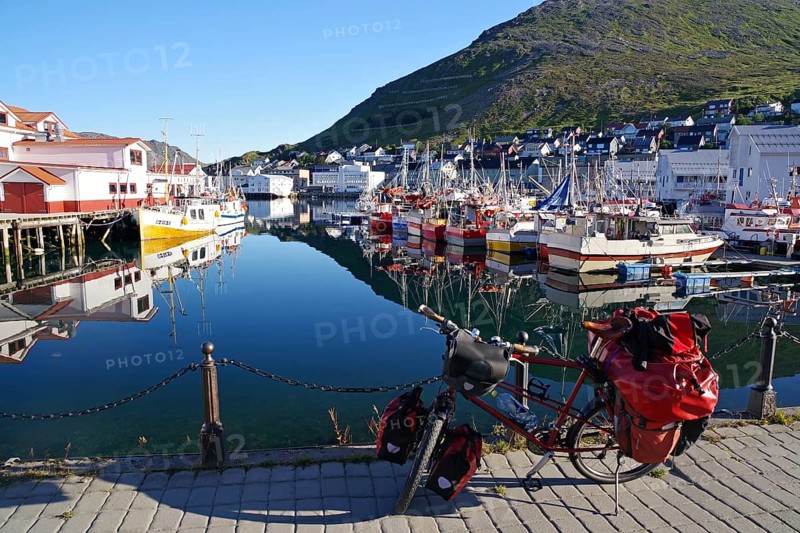 Bicycle in front of harbour with small fishing boats reflected in the calm water