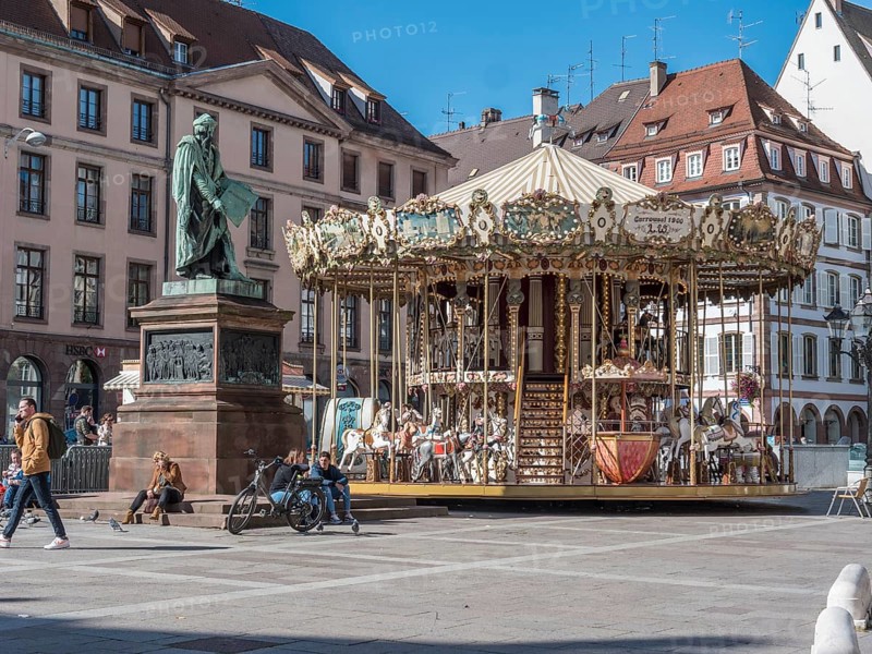 Statue de Johannes Gutenberg and next to him the children's museum carousel Merry go round Gutenberg at Place Gutenberg