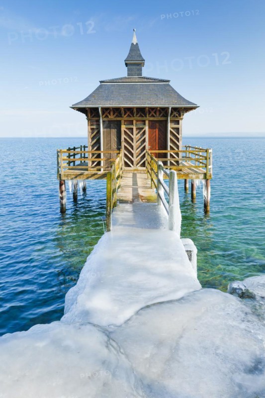Iced wooden bathhouse in sunshine and blue sky on Lake Neuchatel in Gorgier