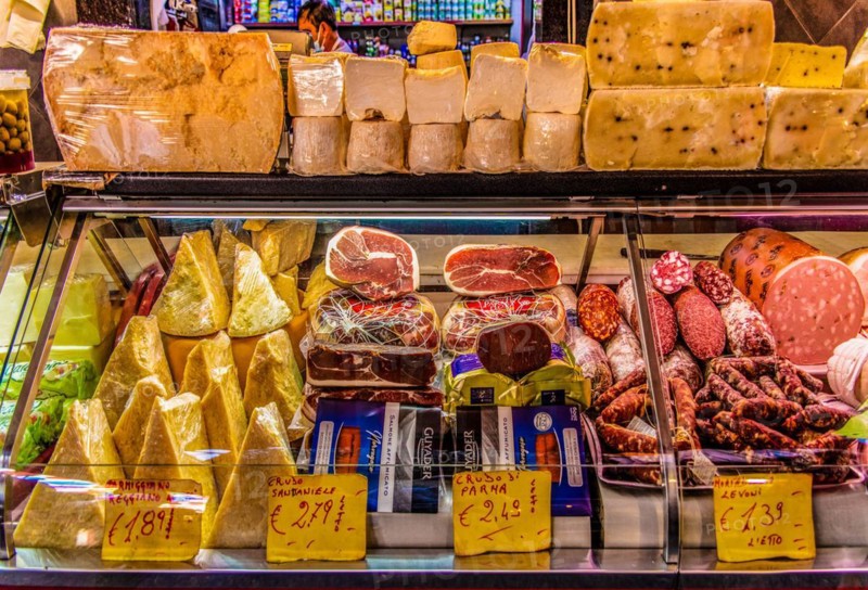 Ham and cheese stall at the historic fish market La pescheria with an abundance of colourful seafood
