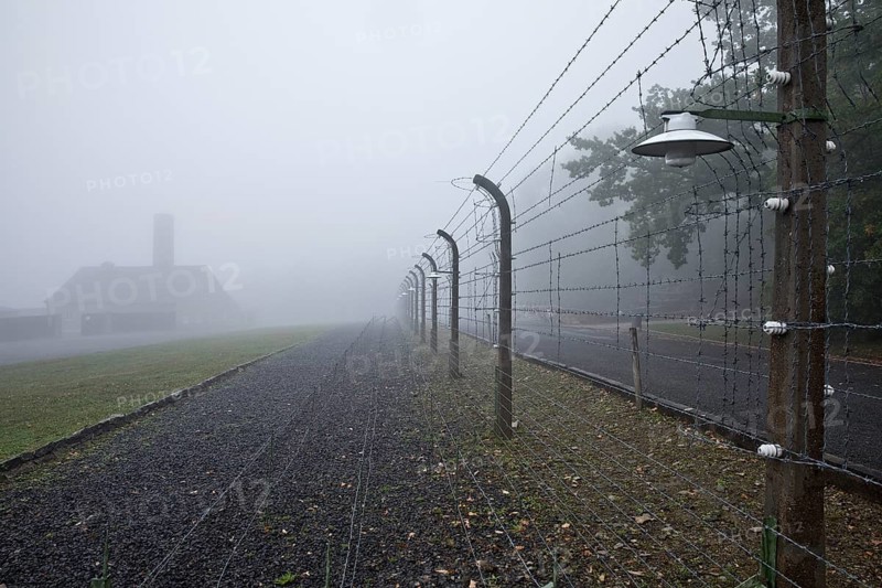 Reconstructed camp fence with crematorium in the fog at beech forest concentration camp