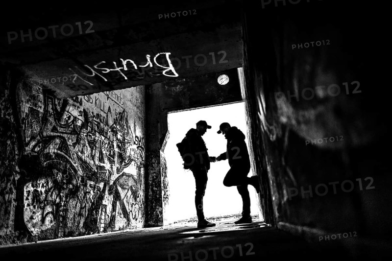 Two men as silhouette in bunker with graffiti walls