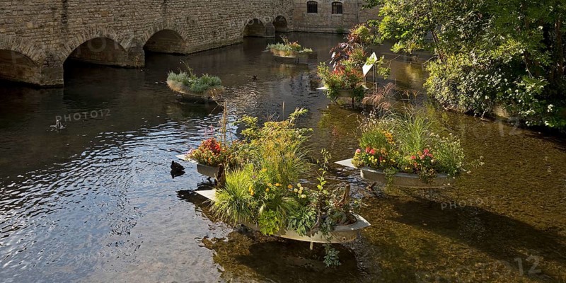 Zinc tubs in the shape of boats with flowering plants on the river Gera