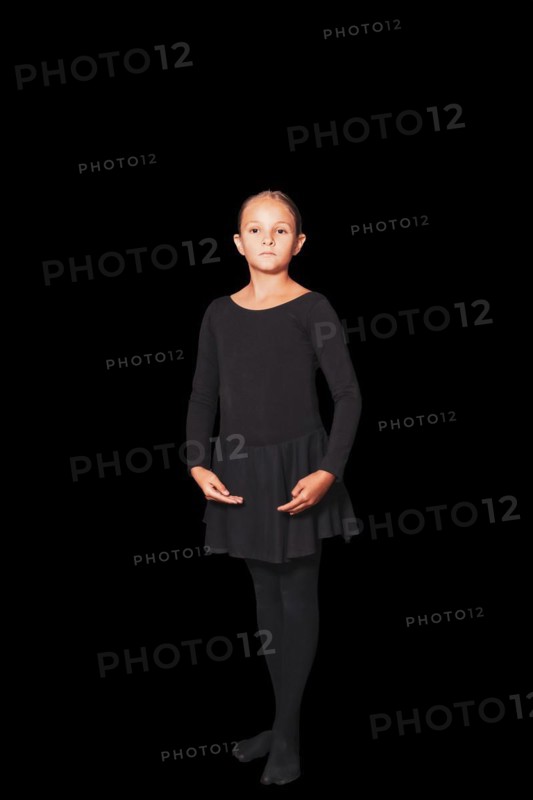Young girl in dancewear stands in position