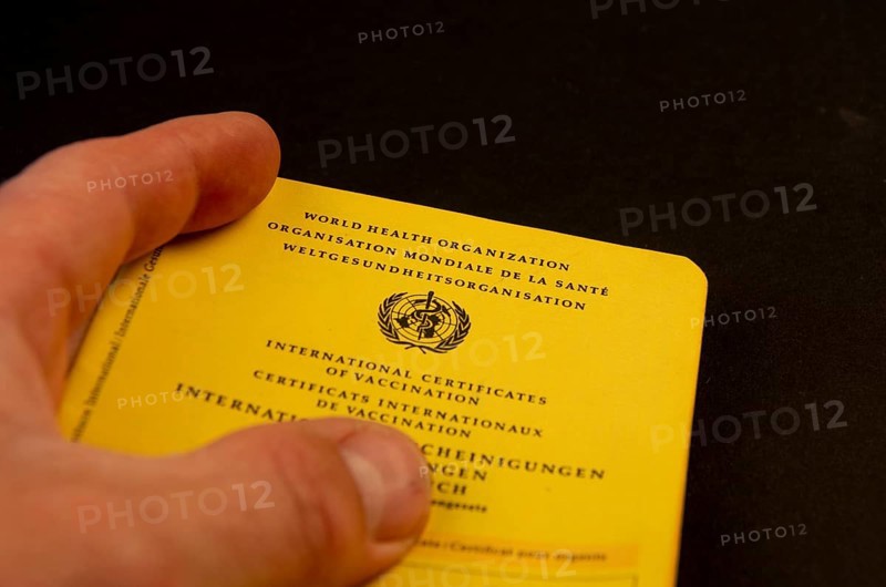 Hand holding a German vaccination certificate against a black background