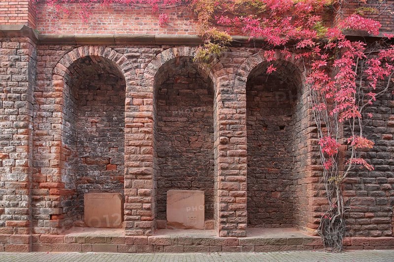 Three archways with clinker stones and stone wall with vines at the church