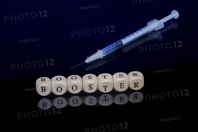 Medical vaccination syringe with the word booster formed from letter cubes on a dark background