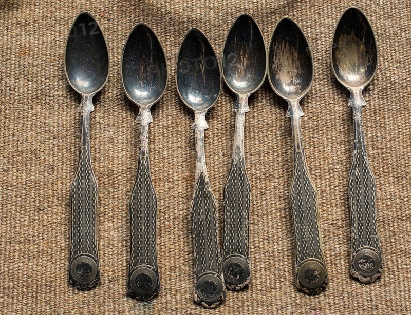 Stylish steel teaspoons on a textured background in display