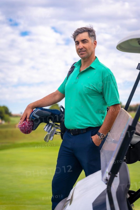 A professional golf player in a green polo shirt with the bag of clubs