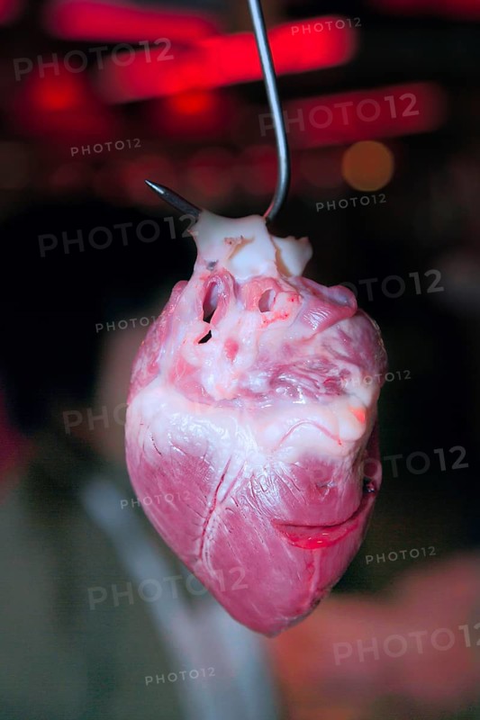 A pig's heart hangs on a hook at a meat counter