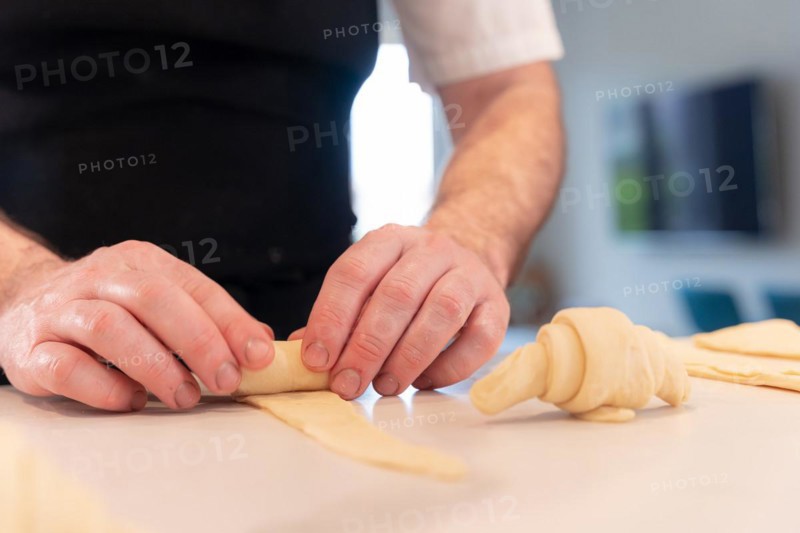 Hands of a man baking small croissants at home