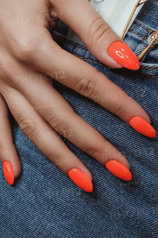 Bright neon manicure on female hands on the background of jeans. Nail design. Beauty hands