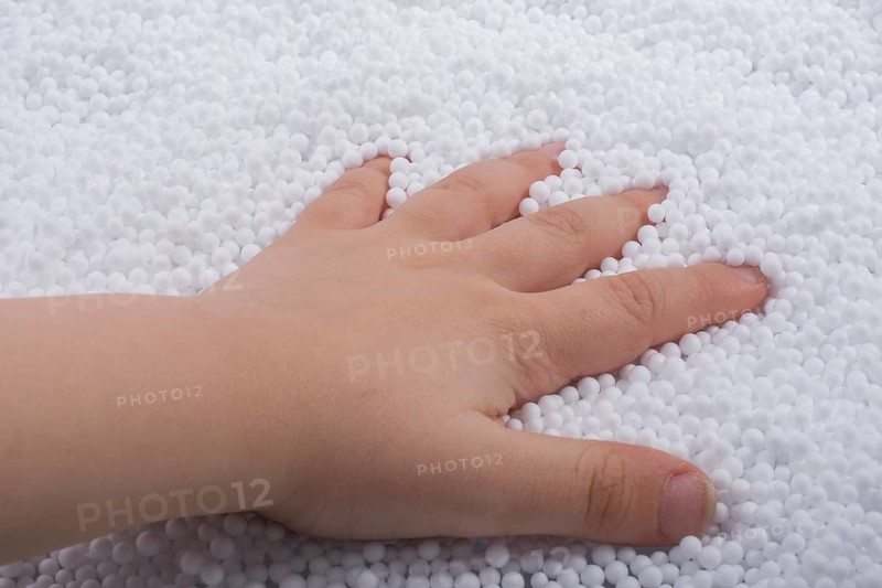 Toddler hand in White polystyrene foam balls as background