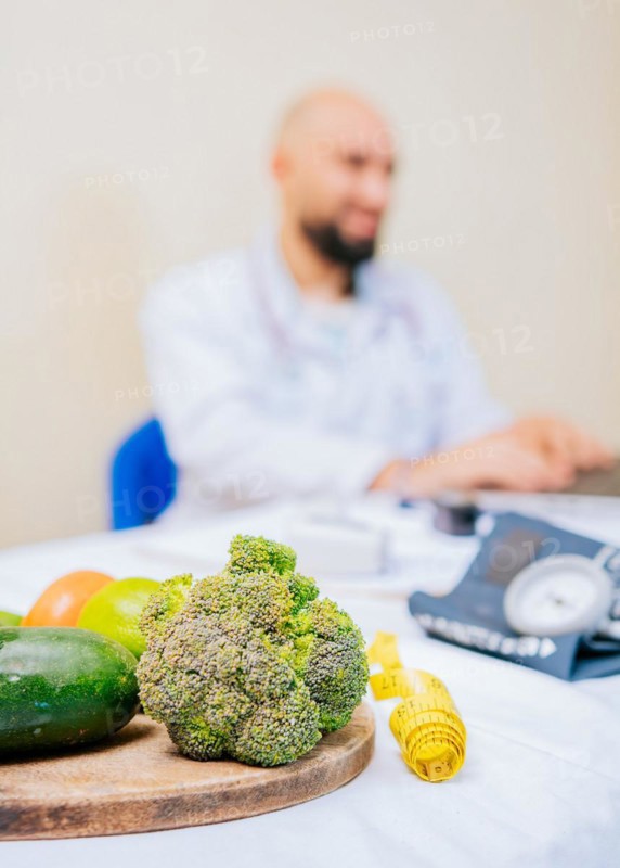 Focus on vegetables of nutritionist with laptop at the desk. Nutritionist working on laptop