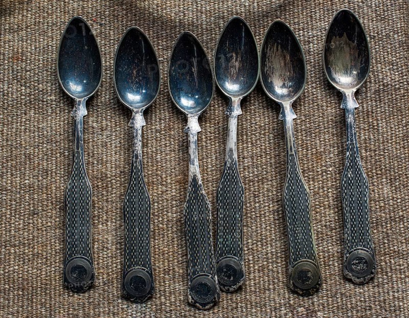 Stylish steel teaspoons on a textured background in display