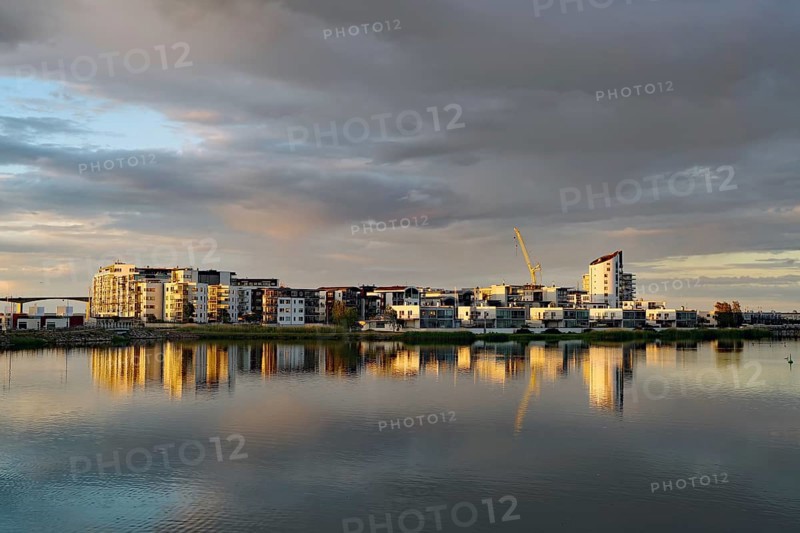 Modern apartment buildings and cranes reflected in the calm Baltic Sea